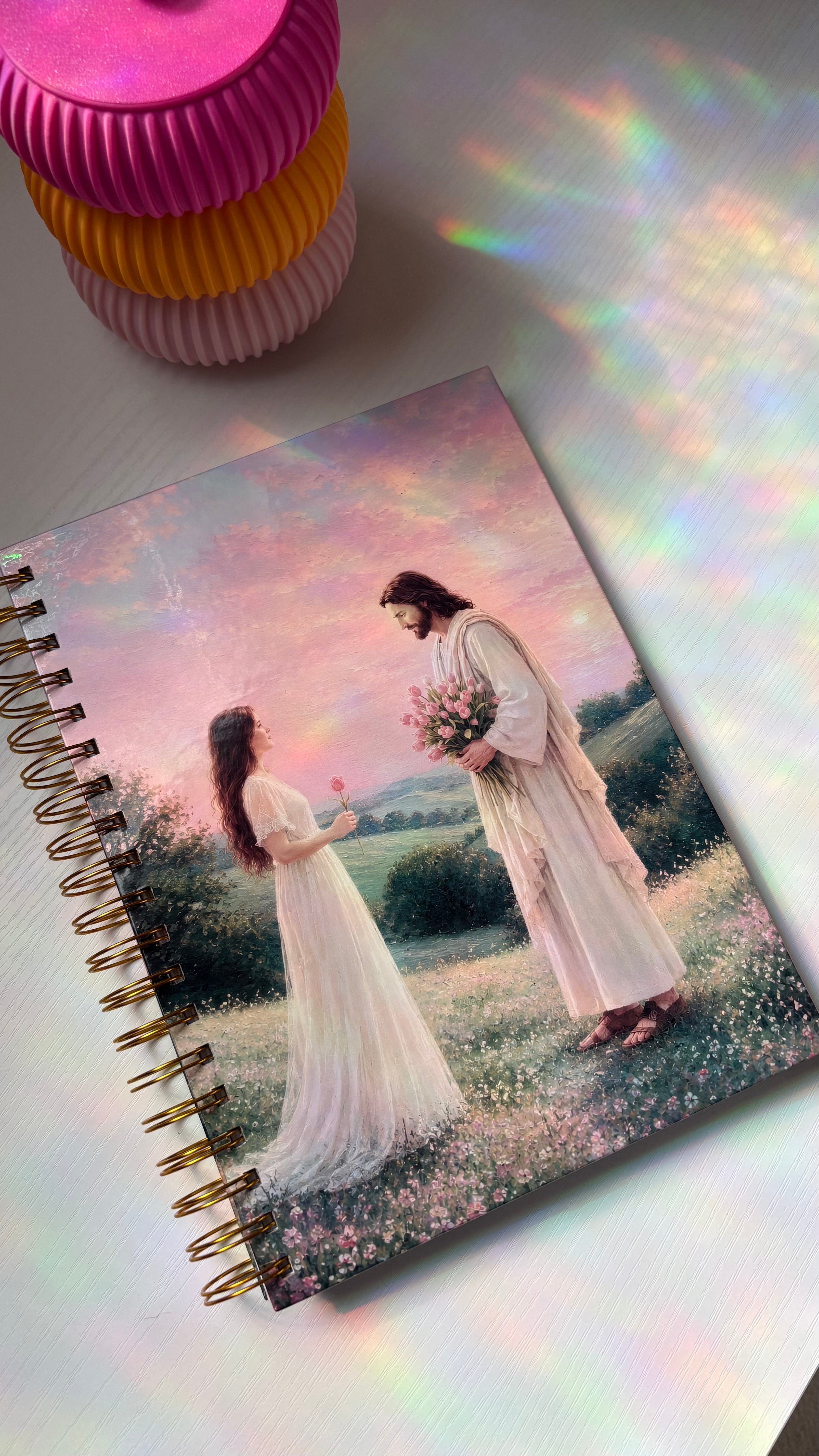 Notebook with a romantic illustration of a couple on a field, with colorful paper cups in the background.