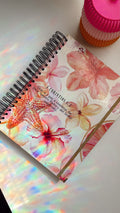 Floral notebook with a pink lid on a white surface