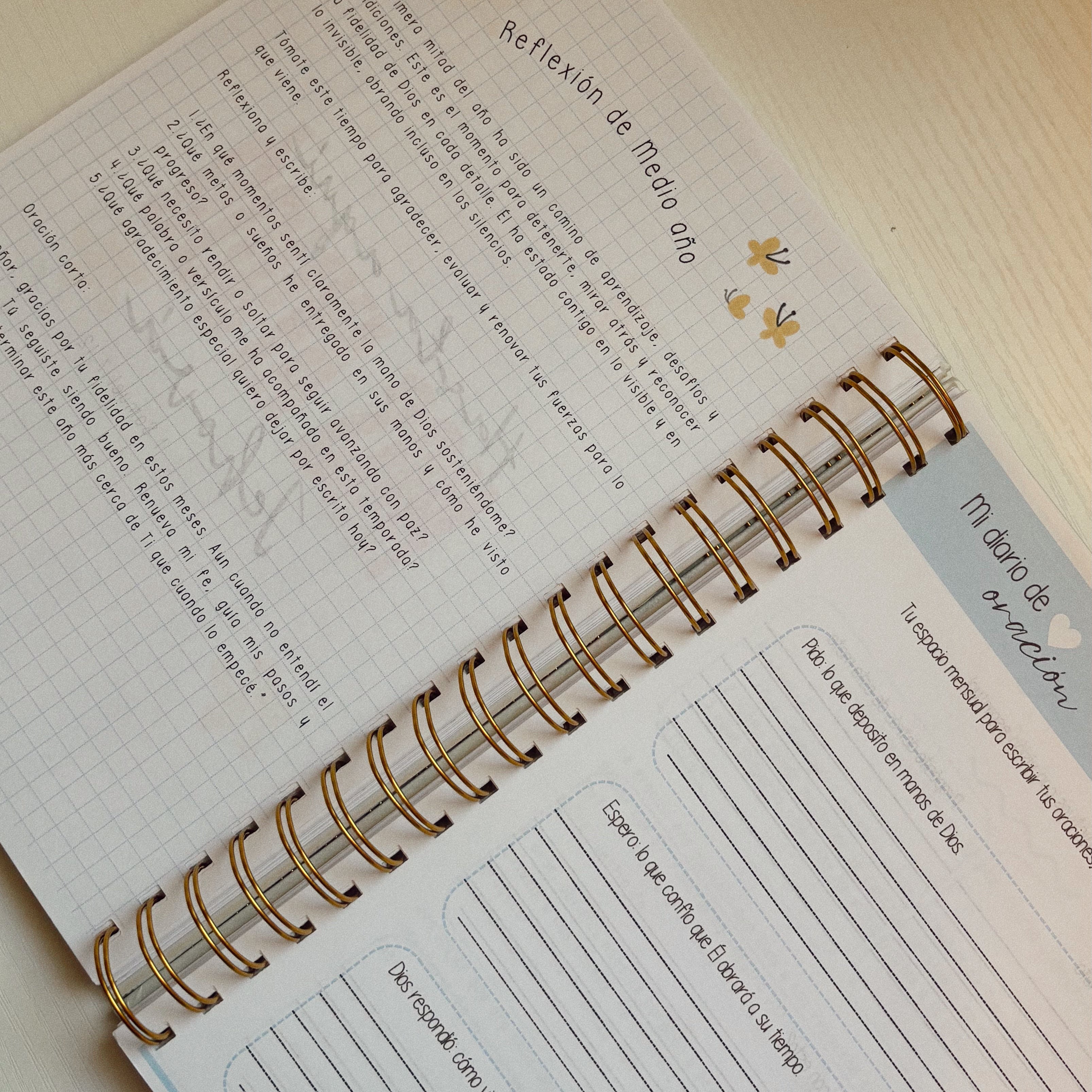 Open spiral-bound notebook on a desk with a red flower-shaped object and computer mouse in the background.