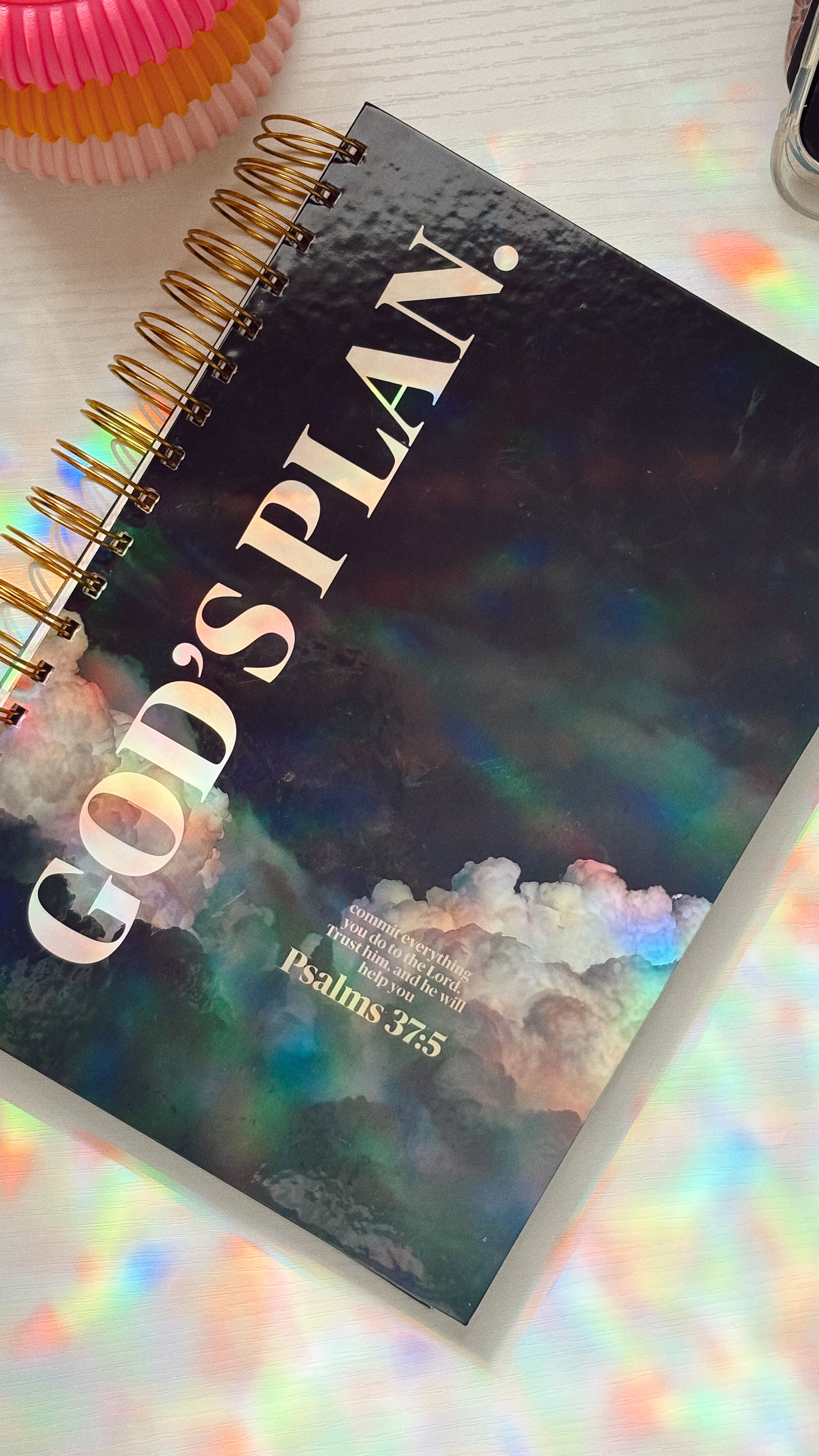 Notebook titled 'God's Plan' with a colorful cover on a white surface.