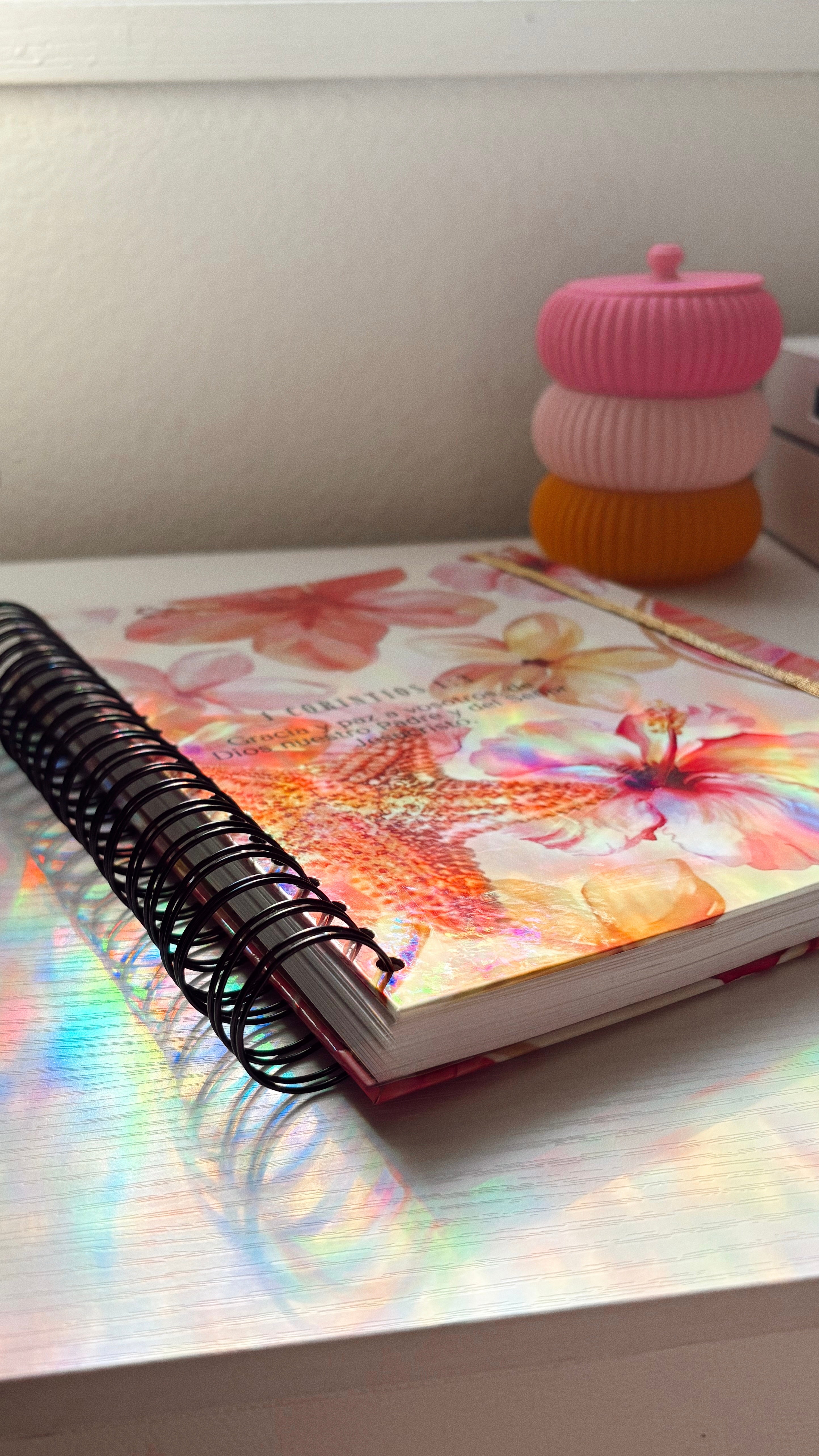 Notebook with floral design on a desk next to a colorful candle