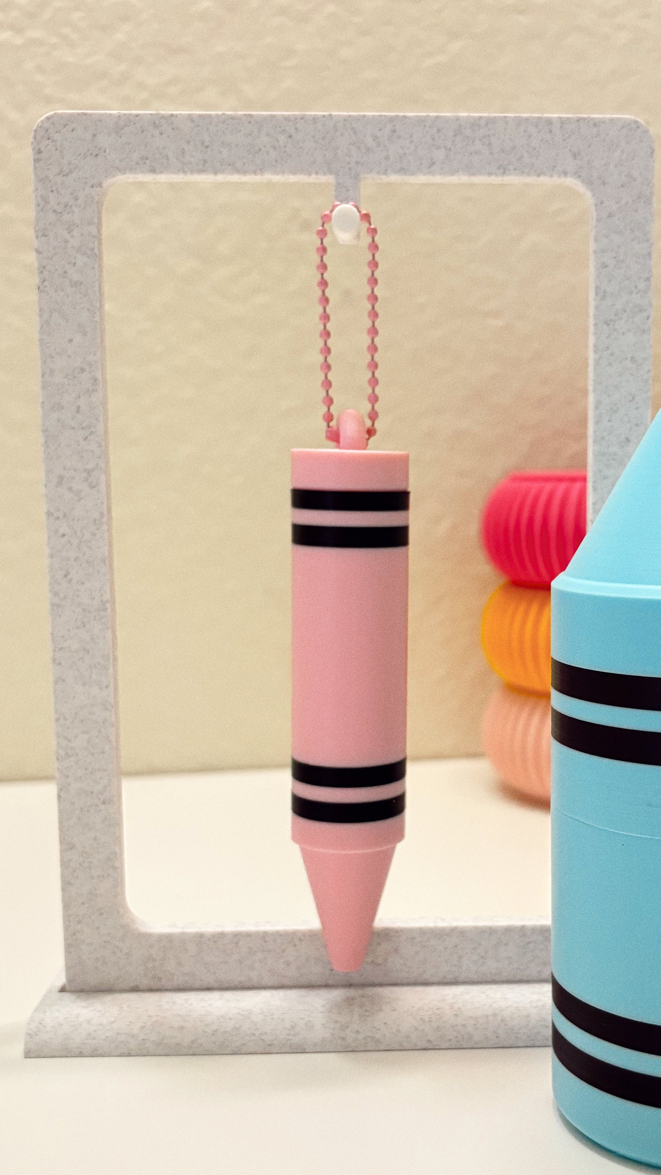 Colorful crayon-shaped keychains with black stripes on a neutral background